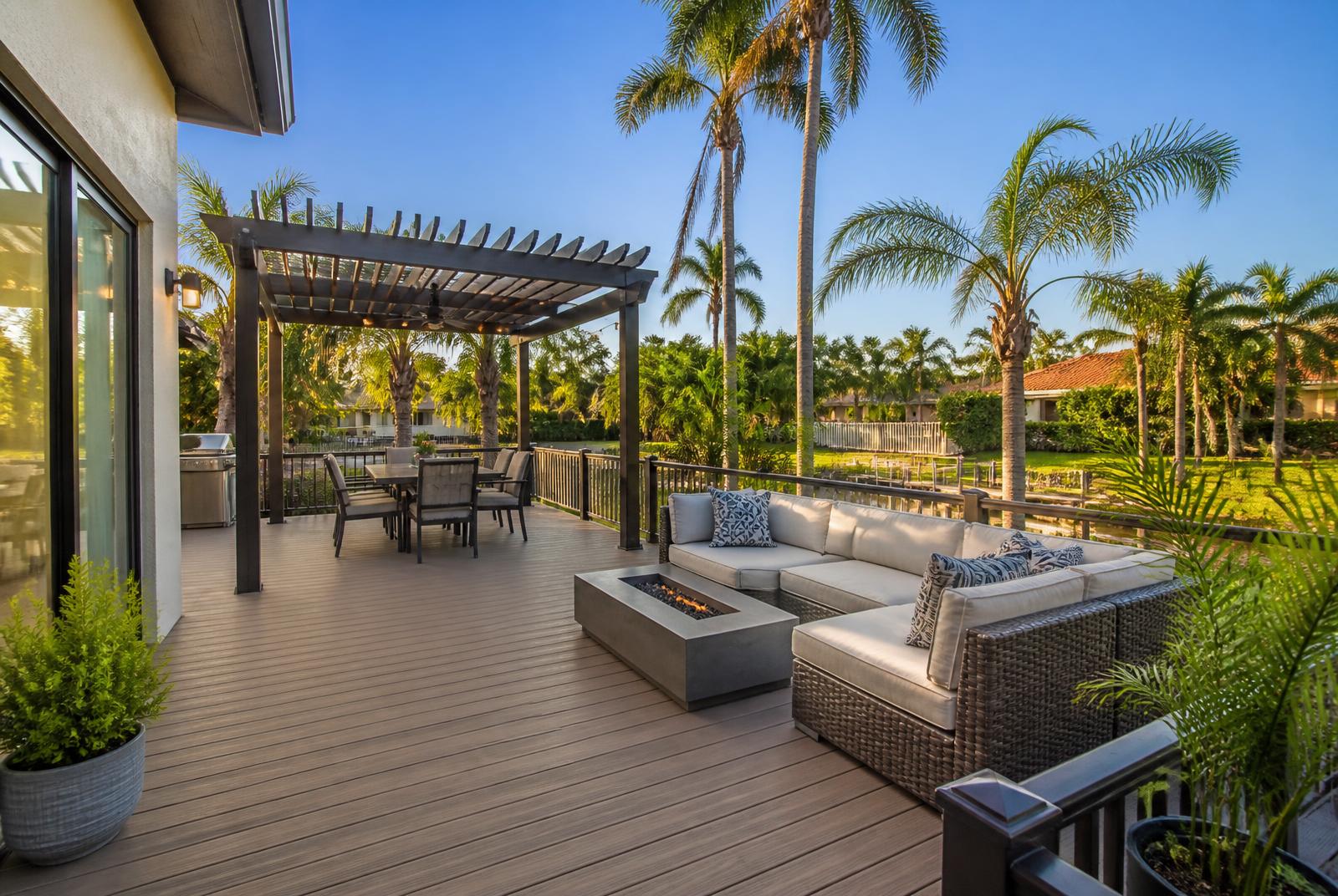 New composite deck with pergola, fire table and outdoor seating behind a Florida home