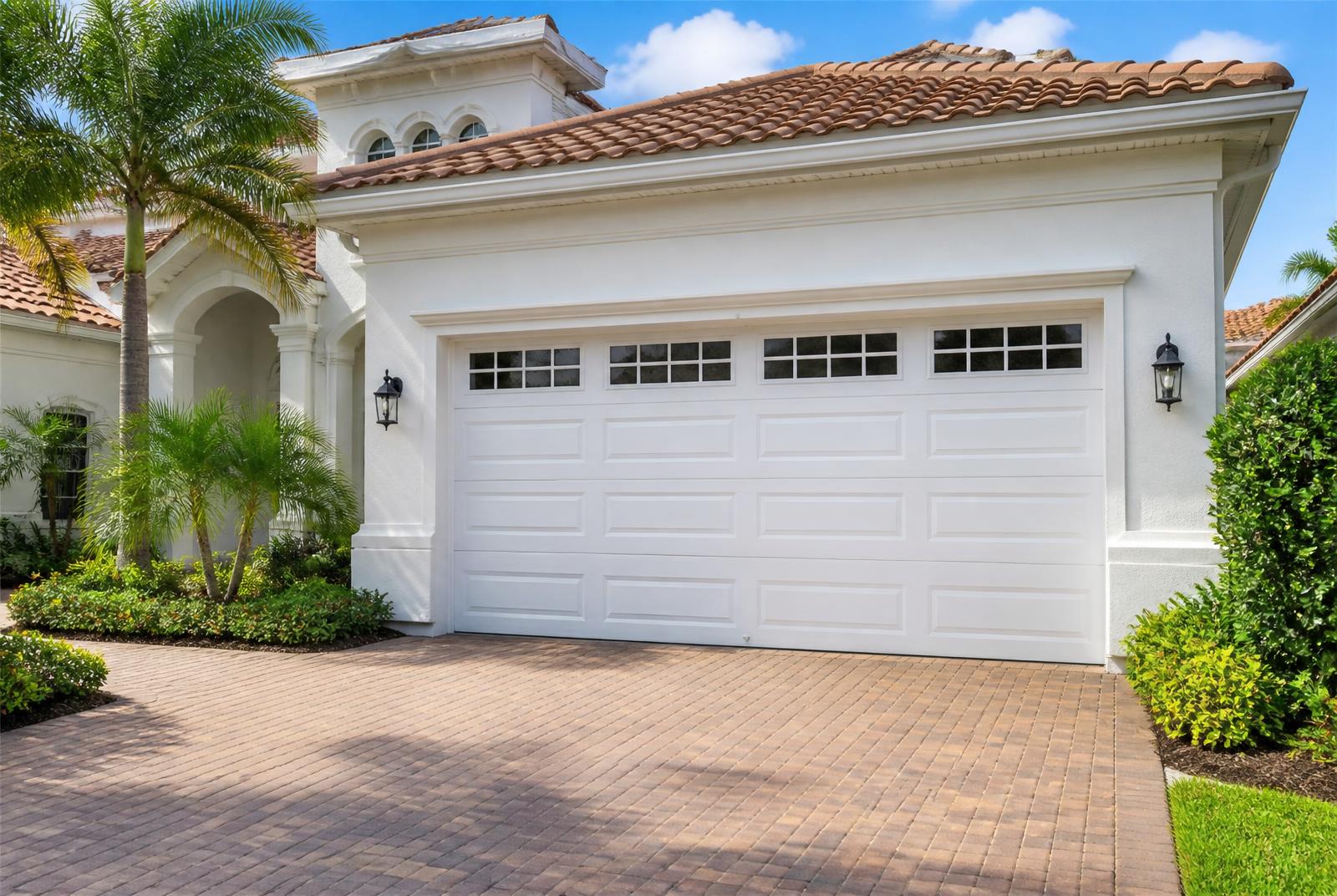 Newly installed white sectional garage door on a Florida stucco home with paver driveway